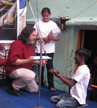 Image of a student handing 
a copy of the essay 'The Future is Ours' to Richard Stallman.